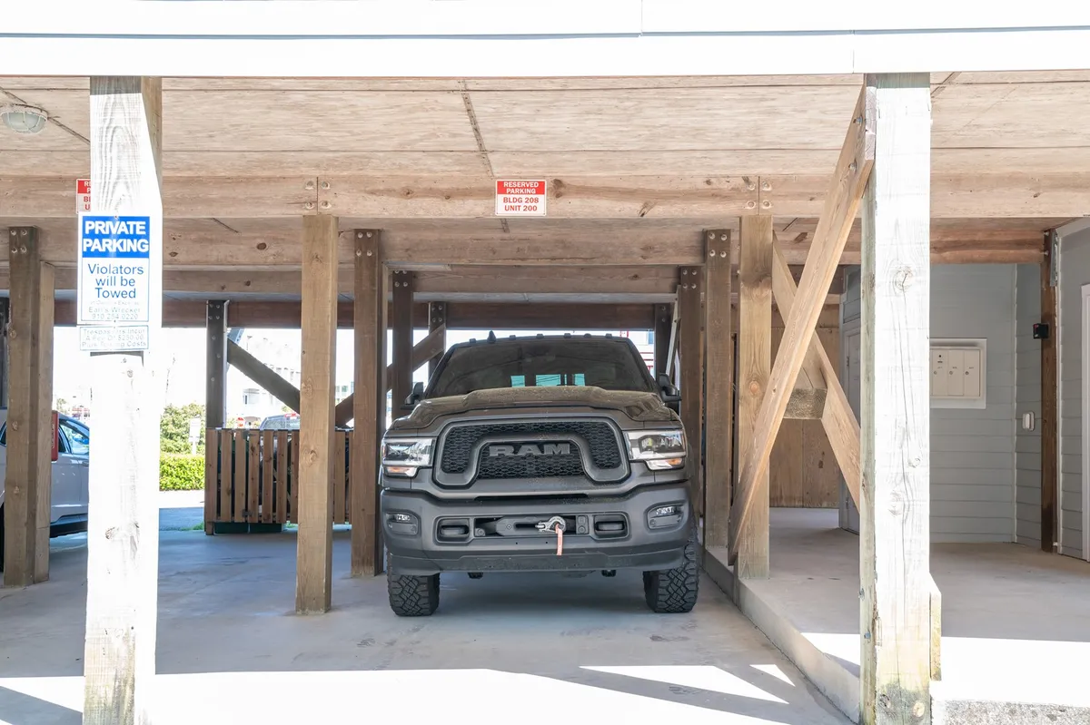 An exterior parking area with a large truck and wooden supports, indicating easy access to the property. The scene suggests convenience for guests arriving by car and provides a sense of place and arrival point.