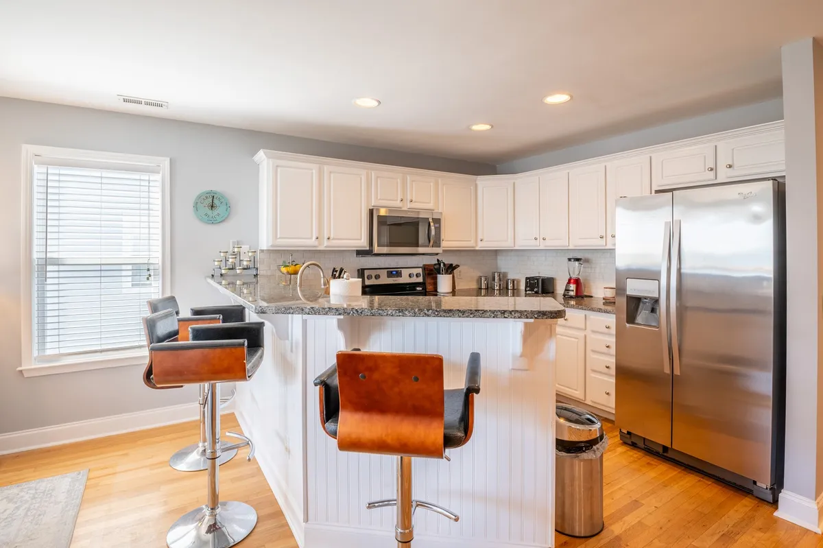 A modern kitchen with a central island, bar stools for casual dining, and gleaming stainless steel appliances. The layout encourages socializing and shared meals, with a warm, welcoming atmosphere ideal for gatherings.